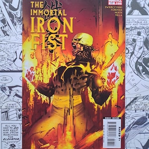 以下が含まれることがあります： コミック「The Immortal Iron Fist」第17号は、黄色いマスクと黒いスーツを身にまとった中心人物が、オレンジと黄色の炎に包まれている様子を描いています。タイトルは炎の背景に黄色と黒の文字で記されています。
