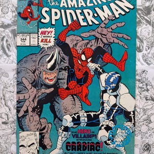May include: The Amazing Spider-Man comic book cover featuring Spider-Man in a battle scene with Rhino and Cardiac. The cover has a teal background with the Marvel Comics logo and issue number 344.