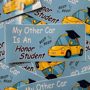 以下が含まれることがあります： 「My Other Car Is An Honor Student」というテキストと、卒業帽をかぶった黄色い車の漫画が描かれた青と黄色のステッカー。車の上に「BEEP BEEP」というテキストがあります。