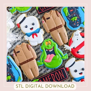 May include: A collection of decorated sugar cookies featuring characters from the Ghostbusters franchise. Cookies include the Stay Puft Marshmallow Man, Slimer, and Ghostbusters uniforms. The image also includes the text "STL DIGITAL DOWNLOAD".