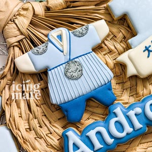 May include: Blue and white decorated cookie in the shape of a traditional Korean hanbok, with the name "Andro" written in blue icing on a separate cookie.