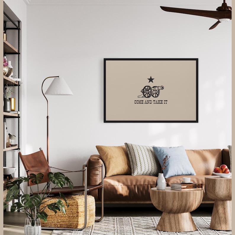May include: A framed print of the "Come and Take It" flag, featuring a black cannon and a single white star on a beige background. The text "Come and Take It" is printed in black below the cannon.