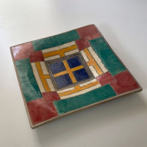 May include: Square ceramic dish with a geometric design in shades of green, red, yellow, blue, and white.