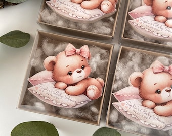 May include: Four small gift boxes with clear lids, each containing a pink and brown teddy bear figurine on a pink pillow. The pillow has the text "Sophie's Baby Shower" and the date "04/06/2024".