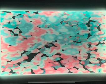 May include: Abstract art print featuring a swirling pattern in shades of pink, blue and white on a black background.