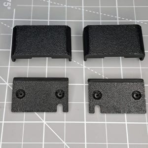 May include: Four black plastic pieces, two are rectangular and two are rectangular with a cut-out on one side.