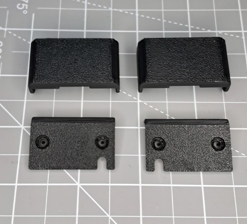 May include: Four black plastic pieces, two are rectangular and two are rectangular with a cut-out on one side.
