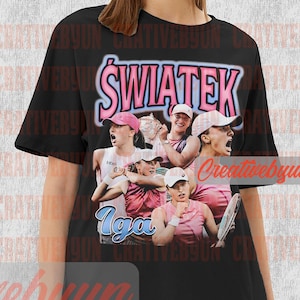 May include: Black t-shirt with a graphic print of a female tennis player, Iga Świątek, in a collage of images. The text "Świątek" is printed in pink letters on the shirt.