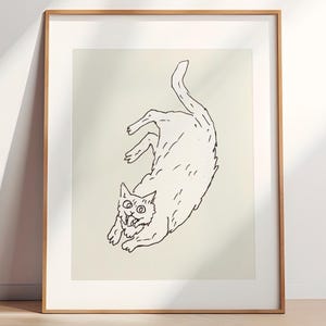 Könnte beinhalten: Gerahmter Kunstdruck mit einer schwarz-weißen Illustration einer Katze in einer spielerischen Pose. Die Katze ist mit ausdrucksstarken Linien gezeichnet, die ihren offenen Mund und ihre großen Augen zeigen. Das Kunstwerk ist vor einem hellen Hintergrund.