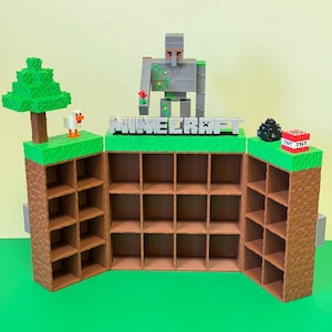 May include: A Minecraft-themed display shelf with multiple cubby holes. The shelf is brown with green accents and features a Minecraft Iron Golem figure, a tree, a duck, and the word "Minecraft". TNT blocks and a creeper are also present.