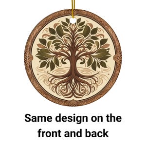 May include: A round ceramic ornament with a brown wooden frame and a detailed image of a tree of life with green leaves and brown roots. The ornament has the same design on both sides.