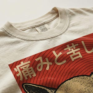 Vintage-style bootleg tshirt design featuring an angry chihuahua shooting red laser beams from its eyes, set against bold Japanese poster graphics with kanji text, distressed 90s aesthetic, and the word “RAGE” in large block letters. Perfect for fans of weirdcore, dreamcore, Harajuku fashion, and unhinged shirts. Printed on soft comfort colors cotton.