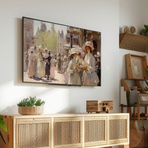 May include: A framed painting of women in hats walking down a street in a city. The painting is in a modern, minimalist living room setting, hanging on a white wall above a wooden cabinet with wicker doors.