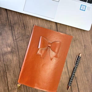 Handgemaakt kunstleer dagboek met gevoerde pagina&#39;s, bladwijzer met strik en maanbedel, platliggend, handgebonden notitieboekje met nepleren omslag