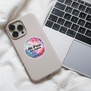 May include: A white phone case with a colourful disco ball sticker that says "All Panic No Disco".