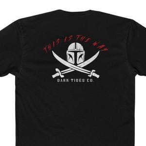 May include: Black t-shirt with a white graphic featuring a Mandalorian helmet, crossed swords, and the text "THIS IS THE WAY" in red. Below the swords is the text "DARK TIDES CO."