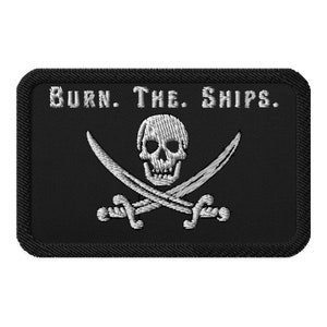 May include: Black embroidered patch with a white skull and crossbones and the text "BURN. THE. SHIPS."