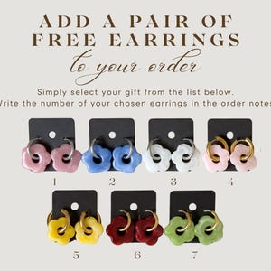May include: Image of seven pairs of flower-shaped earrings in various colors, including pink, blue, white, yellow, red, and green. Each pair is displayed on a black card with a number. The text "ADD A PAIR OF FREE EARRINGS to your order" is at the top.