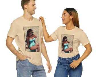 Puede incluir: Una pareja lleva camisetas beige a juego con un estampado gráfico de una mujer en un traje de baño turquesa. La mujer del gráfico está sentada en un muro de ladrillo.