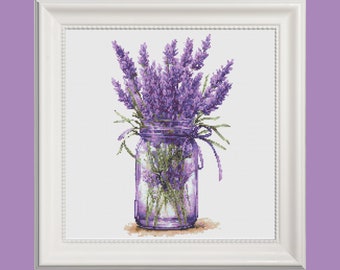 May include: A bouquet of purple lavender flowers in a clear glass jar with a purple lid and a white ribbon tied around the neck.