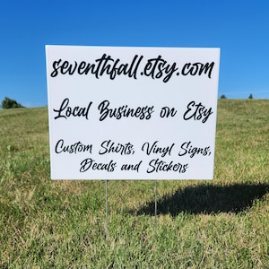 May include: A white sign with black text on metal stakes, set in a grassy field under a blue sky. The sign reads "seventhfall.etsy.com", "Local Business on Etsy", and lists "Custom Shirts, Vinyl Signs, Decals and Stickers".