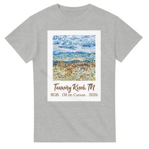 以下が含まれることがあります： 白の長方形の中に風景画が描かれた、ライトグレーのTシャツ。絵は青い空、なだらかな丘、そして野原を描いています。「Tannery Knob, TN」と「RGB. Oil on Canvas. 2026」の文字が下にあります。