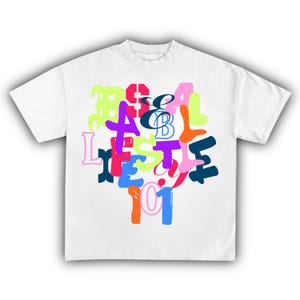 May include: White t-shirt with a colorful graphic design. The design features the words "& B" in a script font, surrounded by other letters and numbers in various bright colors, including pink, blue, green, and orange.