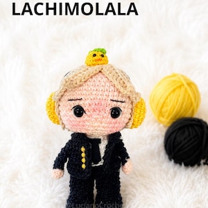 May include: Crocheted doll of a person wearing a black suit with gold buttons, a white shirt, and a small yellow bird on its head. The doll has a light skin tone, black eyes, and rosy cheeks. The text "PARK JIMIN LACHIMOLALA" is at the top.