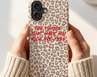 Könnte beinhalten: Eine Handyhülle mit einem beigen und braunen Leopardenmuster und dem roten Text THE THINGS THAT MAKE YOU RICH ARE FREE in der Mitte. Die Hülle hat eine schwarze Aussparung für die Kamera in der oberen linken Ecke.