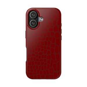 May include: A red phone case featuring a textured, crocodile-style pattern. The case has a dual-lens camera aperture and a smooth, rounded design. The case is designed to protect the phone from damage.