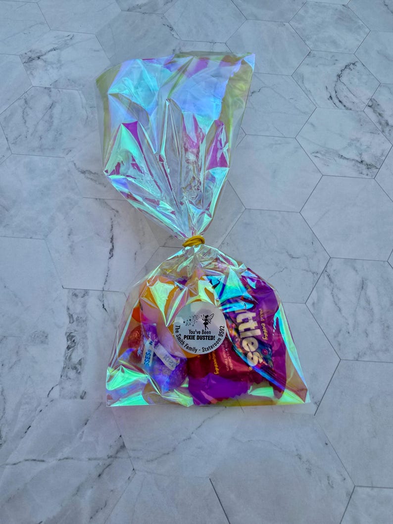 Puede incluir: Una bolsa de pl&aacute;stico transparente e iridiscente llena de caramelos surtidos. La bolsa est&aacute; atada con una banda el&aacute;stica amarilla. Una pegatina redonda blanca con texto negro dice "You've Been Pixie Dusted! The Smith Family - Staten Island".