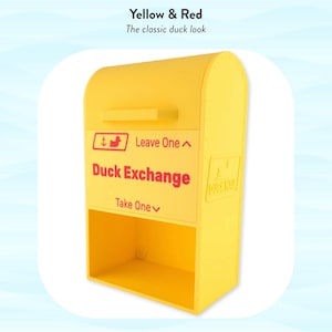 May include: A bright yellow Duck Exchange box with red lettering and a duck logo. The box has a curved top and a lower compartment. Text reads "Leave One" and "Take One".