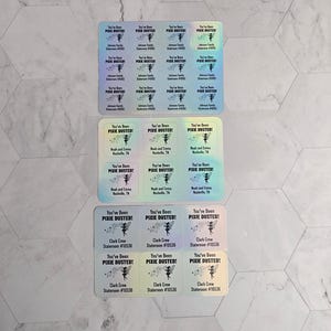 May include: A set of 12 iridescent stickers with the text "You've Been Pixie Dusted!" and a fairy illustration. The stickers are in three rows of four, with each row having a different color scheme. The text "Clark Crew" and "Stateroom #10530" are printed on the bottom row of stickers.