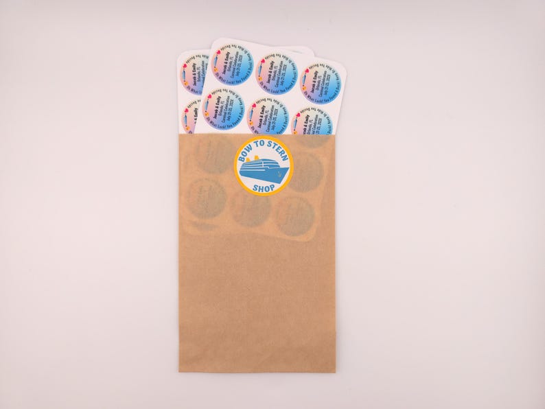 May include: A brown paper bag with a "Bow to Stern Shop" logo and several round stickers. The stickers have a colorful gradient background and text. The bag contains several stickers with the names "Sarah & Kelly" and a date.
