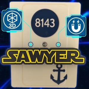 May include: A cream-colored rectangular object with the name "SAWYER" in yellow letters with a black outline. A navy blue circle with the number "8143" is above the name. A navy blue anchor is below the name.