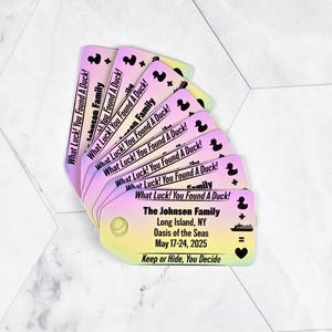 Puede incluir: Una pila de tarjetas coloridas con el texto "What Luck! You Found A Duck!" y un icono de pato de goma. La tarjeta inferior tiene el texto "The Johnson Family, Long Island, NY, Oasis of the Seas, May 17-24, 2025, Keep or Hide, You Decide".