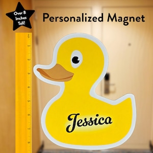 Op de afbeelding: Een gele rubberen eendmagneet met de naam "Jessica" in zwarte cursieve letters. De magneet is meer dan 8 inch hoog.