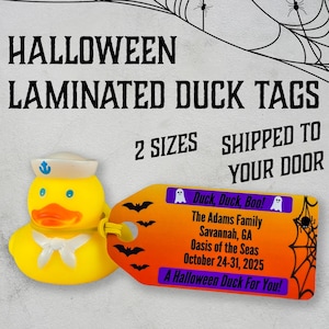 May include: A yellow rubber duck wearing a sailor hat with a blue anchor. The duck is attached to a laminated tag with an orange and black spiderweb design. The tag has the text "Duck, Duck, Boo!" and "A Halloween Duck For You!" in purple text.