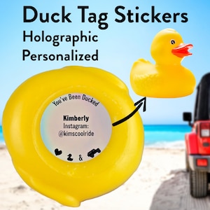 May include: A yellow holographic sticker with the text "You've Been Ducked" and the words "Kimberly Instagram: @kimscoolride". The sticker features a small heart, a duck, and a jeep icon. The sticker is on a yellow rubber duck.