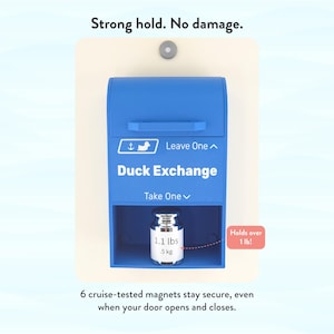 May include: A blue Duck Exchange box with the text "Leave One" and "Take One". The box holds a silver object that weighs 1.1 lbs (5 kg). The text "Strong hold. No damage." is at the top. The text "Holds over 1 lb!" is on the right.