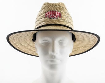 May include: A straw hat with a wide brim and a black trim. The hat features the text "Haggard Texas" in red and white on the front. The hat is displayed on a white mannequin head.
