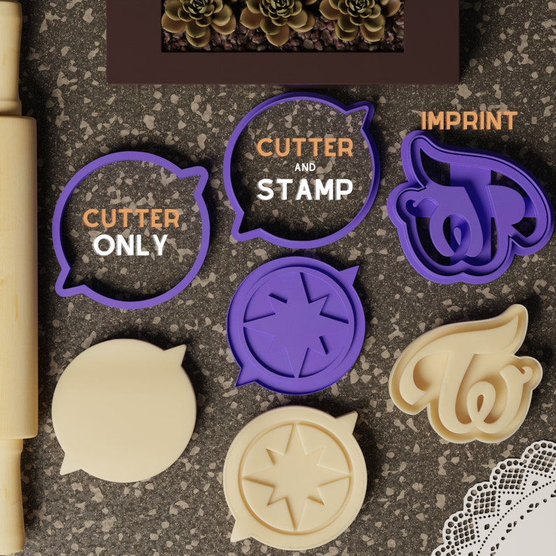Op de afbeelding: Paarse en witte koekjesvormen in de vorm van een spraakballon, een ster en het woord "Twice". De vormen liggen op een grijs, getextureerd oppervlak. De tekst op de spraakballon zegt "Cutter and Stamp". Een andere spraakballon zegt "Cutter Only".