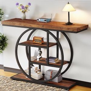 May include: A brown wooden console table with a black metal frame and circular shelves. The table has a distressed wood finish and a modern industrial design.
