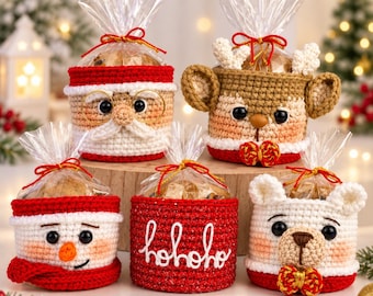 Puede incluir: Cinco cestas de regalo de ganchillo con diseños navideños: un Santa Claus con gafas, un reno con astas, un muñeco de nieve con bufanda, una cesta roja con texto hohoho blanco y un oso blanco con lazo, envueltas en plástico transparente.