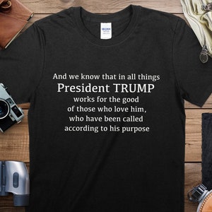 Puede incluir: Camiseta negra con texto blanco que dice "And we know that in all things President TRUMP works for the good of those who love him, who have been called according to his purpose."