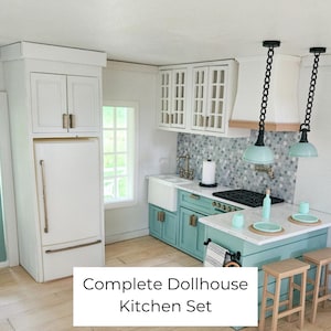 May include: A miniature dollhouse kitchen set featuring a white refrigerator, teal lower cabinets, white upper cabinets with glass panes, a white farmhouse sink, a kitchen island with two wooden stools, and two hanging pendant lights with chain details.