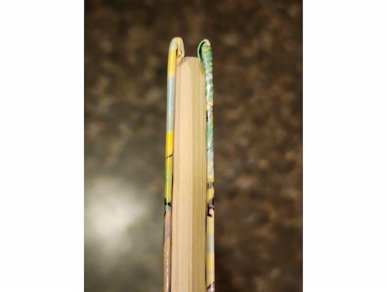 Puede incluir: Primer plano del lomo de un libro de tapa dura con una cubierta estampada en amarillo, verde y blanco.