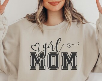 May include: A beige sweatshirt with the text "girl MOM" in black lettering with a heart above the word "girl".