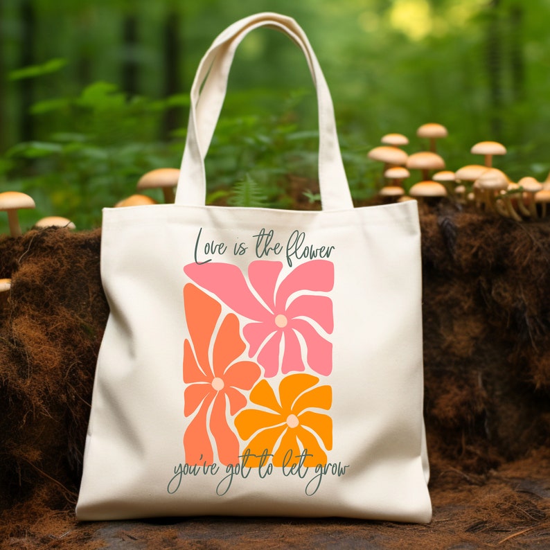 May include: A white canvas tote bag with the text "Love is the flower you've got to let grow" and a graphic of three stylized flowers in pink, orange, and yellow.