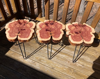 May include: Three wooden stools with a natural wood finish and a reddish-brown heartwood. The stools have a unique, organic shape and are supported by black hairpin legs.